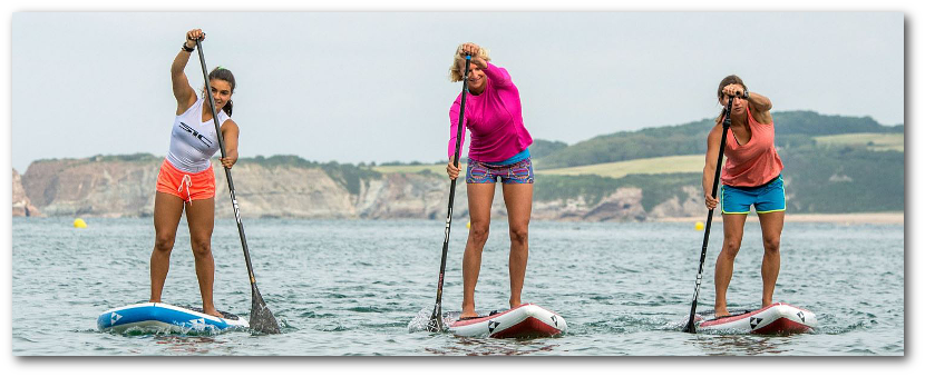 Three lady friends stand up paddle boarding together.